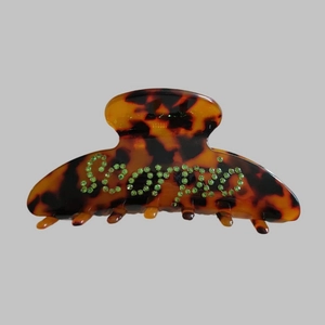 Detailed view of Scorpio lettering in green rhinestones on tortoise shell hair claw