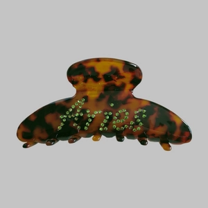Macro shot of large tortoiseshell hair claw clip with green rhinestone Aries lettering