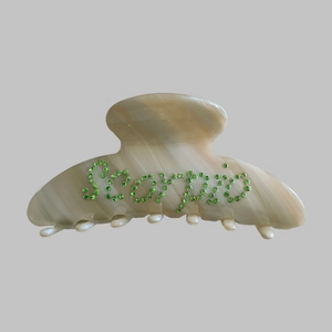 Macro detail of Scorpio hair claw clip with green rhinestones and marble texture