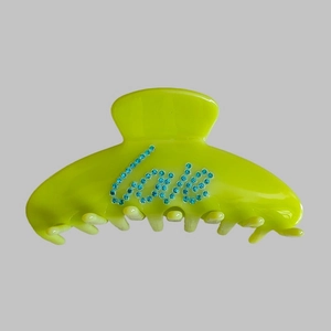 Detail of neon green resin claw clip featuring blue rhinestone LOVE letter decoration