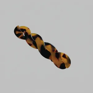 Détail de la barrette à cheveux en acétate au motif écaille et design spirale vague