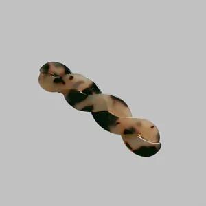 Détail d'une pince à cheveux torsadée en acétate avec motif écaille de tortue ambrée