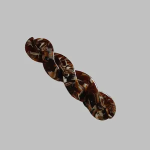 Détail d'une barrette à cheveux torsadée en acétate avec motif écaille de tortue et vagues