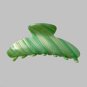 Gros plan d'une grande pince à cheveux en acétate marbré vert avec une finition polie