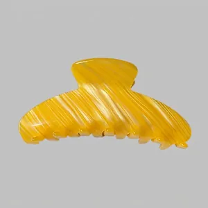 Grosse pince à cheveux en acétate ambré montrant la texture polie et le ressort interne