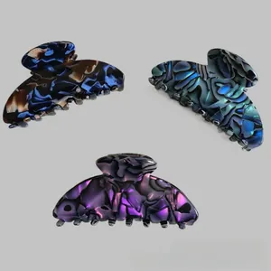 Detailed macro view of three marbled acetate hair claws with premium iridescent finish