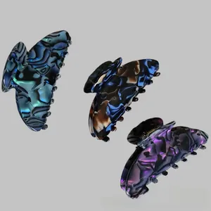Macro view of three acetate butterfly hair claws with marble textures and metal springs