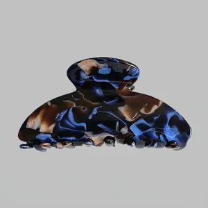 Macro detail of large acetate hair claw clip featuring blue and brown marble texture pattern