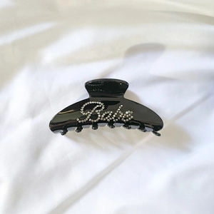 Vue détaillée d'une grande pince à cheveux noire avec inscription Babe en strass brillant