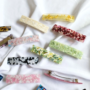 Assorted French acetate hair clips in marble and floral patterns on white cloth