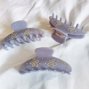 Macro detail of purple acetic acid flower hair claws with sparkling rhinestone stars
