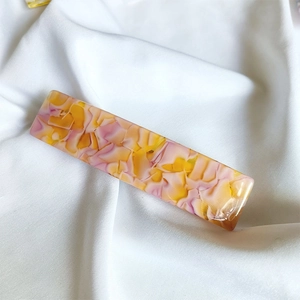Macro shot of rectangular acetate hair clip with pink and yellow marble texture finish