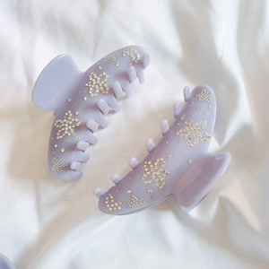 Set of two purple flower hair claws with rhinestones on a white fabric background