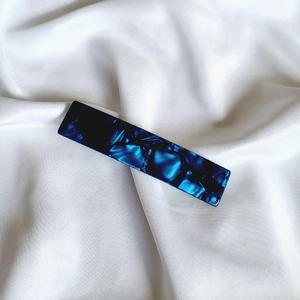 Detailed close-up of dark blue marble texture on a sleek acetate rectangular hair clip