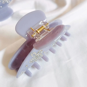 Close-up of lavender acetate hair claw clip with rhinestones and gold spring