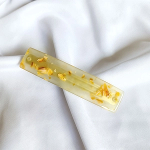 Close-up of a French acetate hair clip featuring embedded dried yellow flower petals