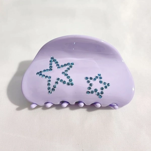 Détail d'une pince à cheveux lavande en acétate ornée de strass bleus en forme d'étoile