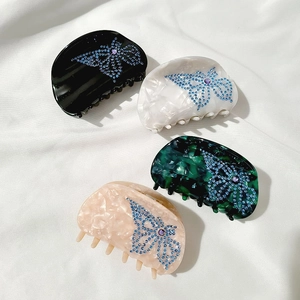 Macro shot of four colorful acetate hair claws with blue rhinestone butterfly patterns