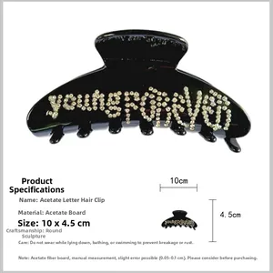 Dettaglio di pinza per capelli in acetato nero da 10cm con scritta Young Forever in strass