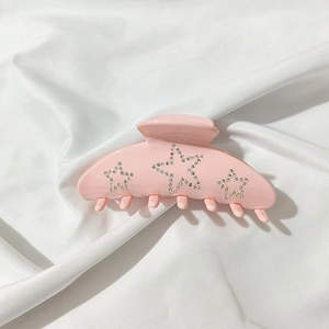 Detail of a pink acetate hair claw clip featuring sparkling rhinestone star decorations