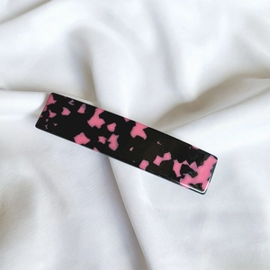 Detail shot of French acetate hair clip with pink tortoiseshell pattern on white silk