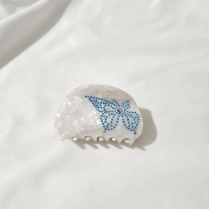 Close-up of semi-circle resin hair claw with blue rhinestone butterfly and purple gemstone
