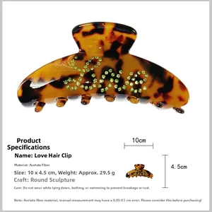 Detail view showing large tortoiseshell hair claw clip with Love rhinestone inlay