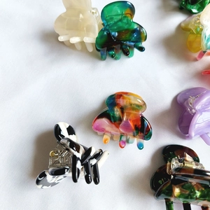 Mini acetate hair claws in various colors like marble and tortoise on white fabric