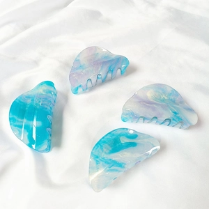Detailed view of four cloud-shaped acrylic hair claws with blue and purple marble texture
