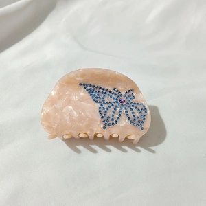 Detailed macro view of the semicircular pink marble acetate hair claw with butterfly crystals
