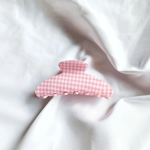 Détail d'une pince à cheveux à carreaux rose et blanc montrant les dents de fixation