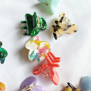 Detailed close-up of colorful mini acetate hair claw clips in various patterns and marble colors