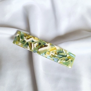 Macro detail of French acetate ponytail hair clip with colorful marble pattern on silk