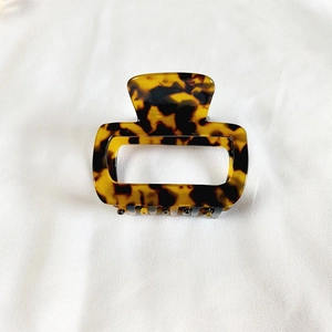 Detailed macro shot of a tortoise shell acetate hair claw clip on white fabric