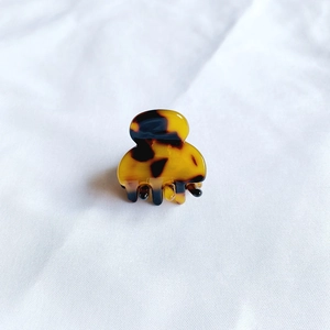Close-up of tortoise shell pattern acetate mini hair claw clip on white fabric