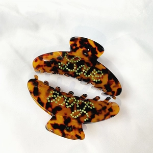 Set of two large tortoiseshell hair claws with green crystal love letters on white fabric