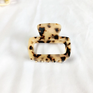 Detail view of square tortoiseshell acetate hair claw clip on soft white fabric background