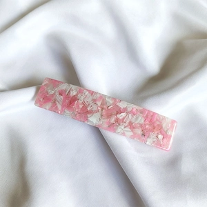 Detailed close-up of pink and white acetate hair clip with marble texture on velvet