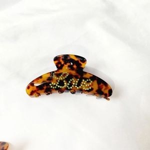 Detailed view of tortoiseshell hair claw clip with green rhinestone LOVE lettering