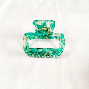 Detail of square emerald green and pearl white marbled hair claw with polished finish