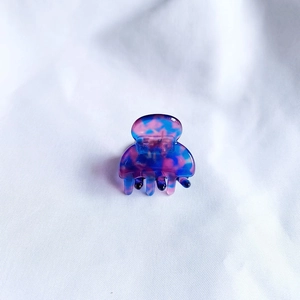 Detail view of mini marble patterned acetate hair claw clip with colorful tie-dye design