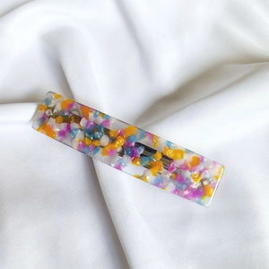 Detailed close-up of a French rectangular acetate hair clip with colorful mosaic inlay