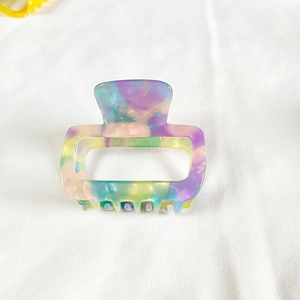 Detail view of small square acetate hair claw clip with colorful marble tie-dye pattern