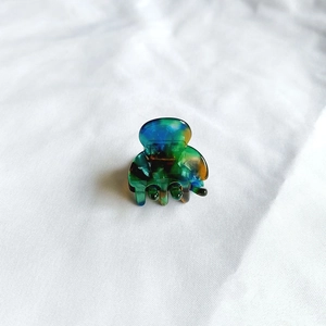 Close-up of a mini acetate hair claw clip with colorful marble texture on white fabric