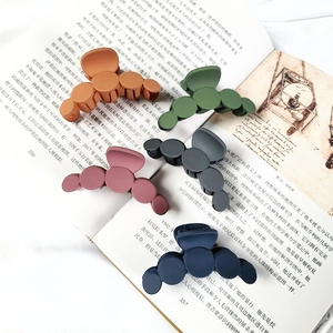 Detailed view of large matte hair claws in five colors resting on an open book