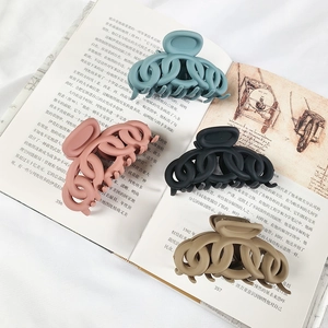 Set of four matte hollow chain hair claws in blue, pink, black, and khaki on a book