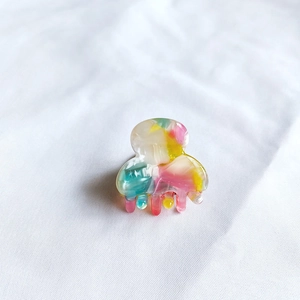 Close-up of small acetate hair claw clip with colorful marble pattern and smooth resin texture