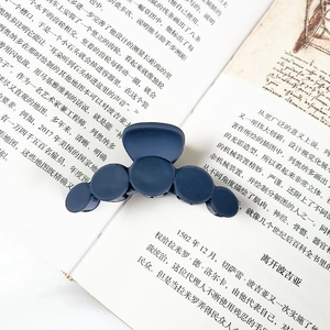 Macro shot of matte dark blue round hair claw clip on an open book background