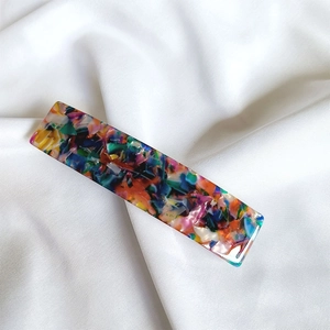 Detail of rectangular acetate hair clip with colorful marble pattern on silk