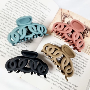 Close-up of matte hair claw clips in pastel colors on vintage book pages backdrop